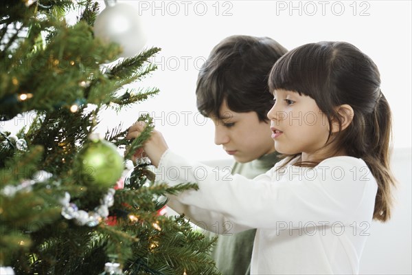 Hispanic brother and sister decorating Christmas tree