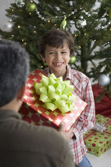 Hispanic boy giving Christmas gift to father