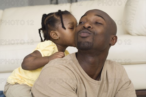 African girl kissing father's cheek