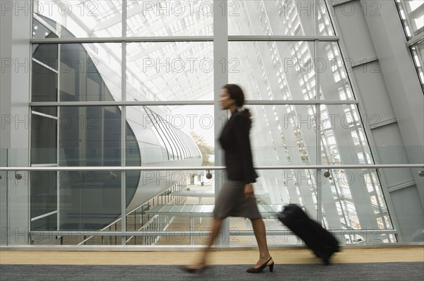 Hispanic businesswoman pulling suitcase