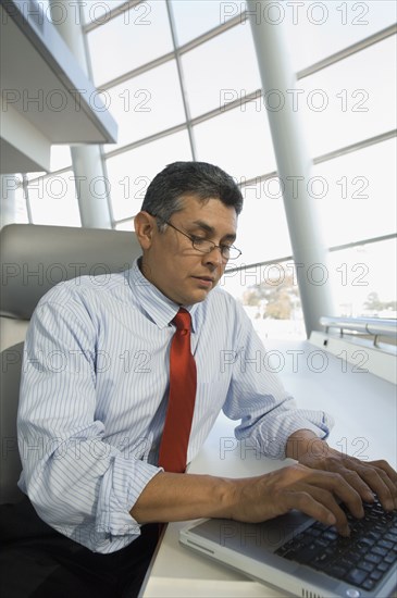 Hispanic businessman typing on laptop