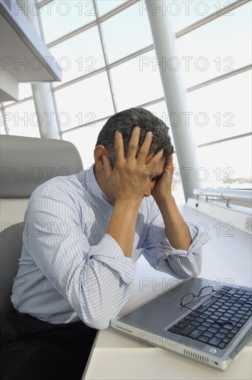 Hispanic businessman with head in hands