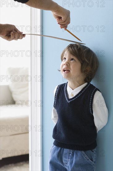 Asian boy having height measured on wall