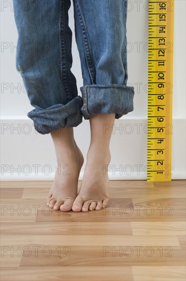 Boy standing on tiptoes next to ruler