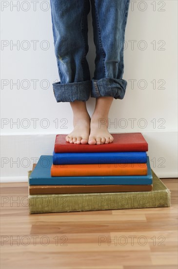 Boy standing on stack of books