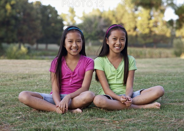 Asian twin girls smiling outdoors