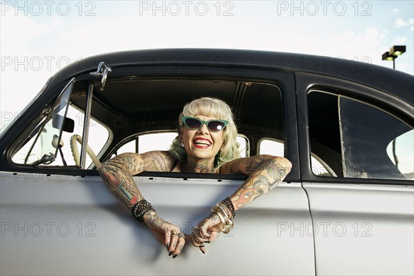 Woman with tattoos leaning out window of 1951 Chevy