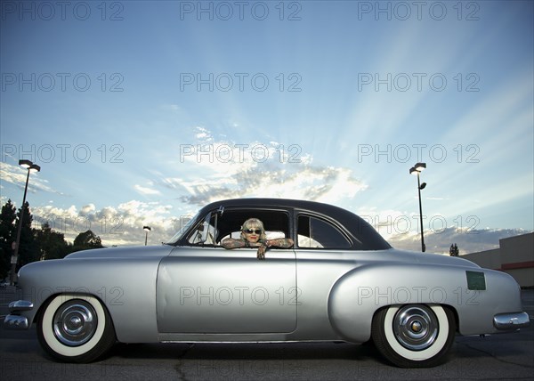 Woman with tattoos leaning out window of 1951 Chevy
