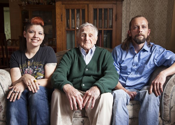 Caucasian couple and older man smiling on sofa