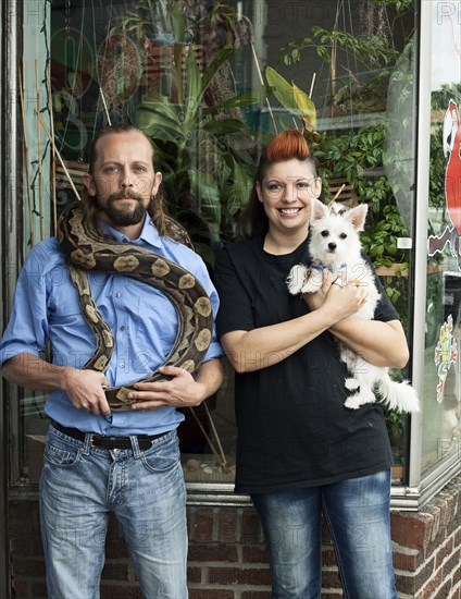 Caucasian couple holding pets outdoors