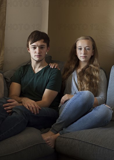 Caucasian brother and sister smiling on sofa