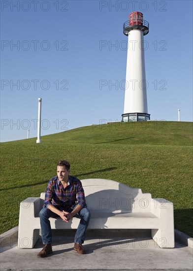 Man sitting on park bench near lighthouse