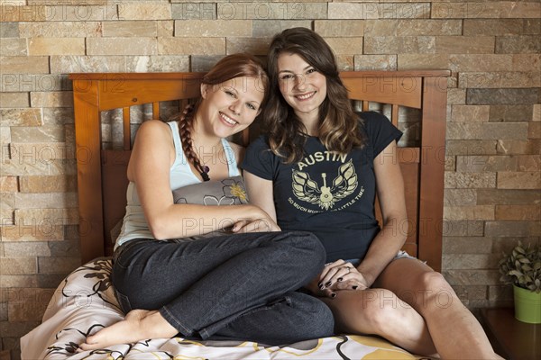 Students hugging on bed in dorm room