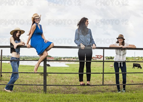 Caucasian women standing on ranch gate