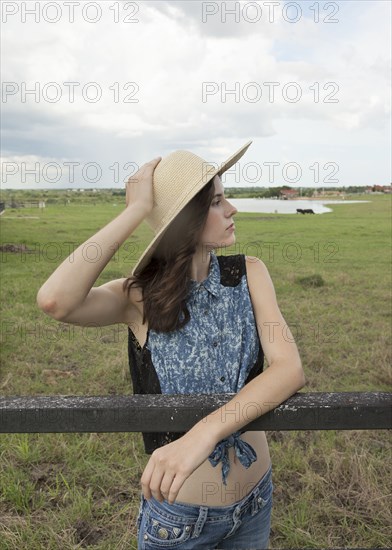 Caucasian woman leaning on fence in rural pasture