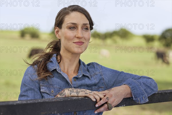 Caucasian woman leaning on fence in rural pasture