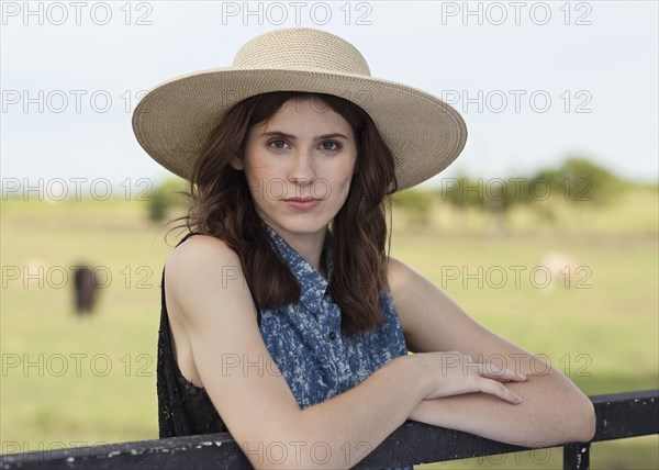 Caucasian woman leaning on fence in rural pasture