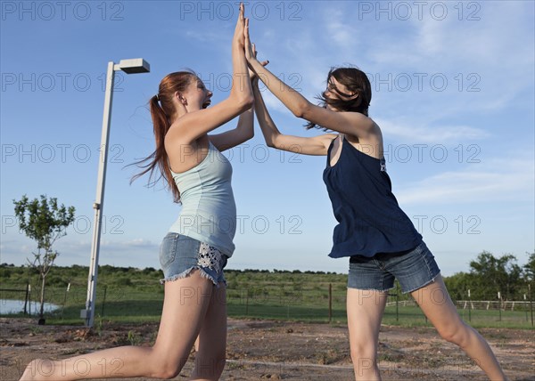 Caucasian women high fiving in rural field