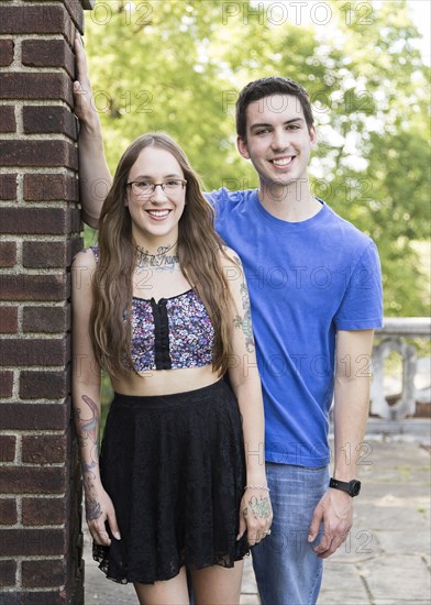 Caucasian couple leaning on wall at park