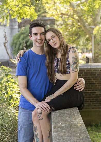 Caucasian couple posing on wall at park