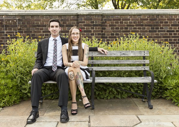 Well-dressed Caucasian couple sitting on bench at park