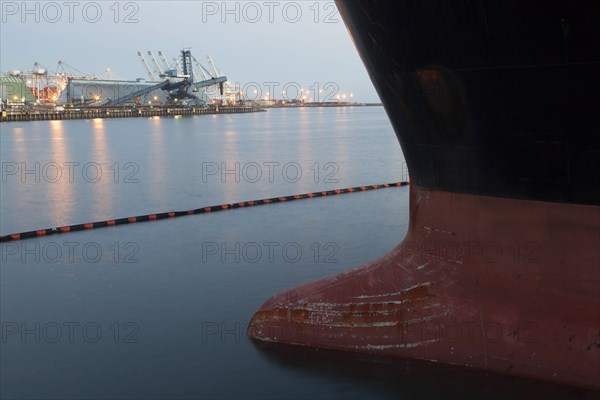 Close up of bow of ship docked in industrial harbor