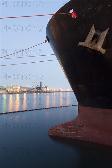 Close up of bow of ship docked in industrial harbor