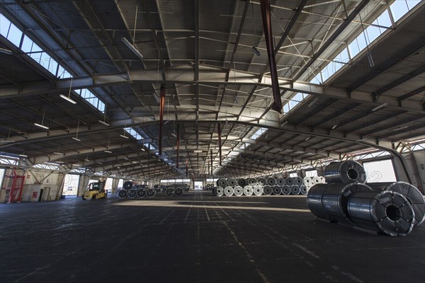 Metal rolls and forklift in warehouse