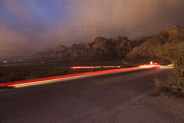 Curving light trails on street near mountain