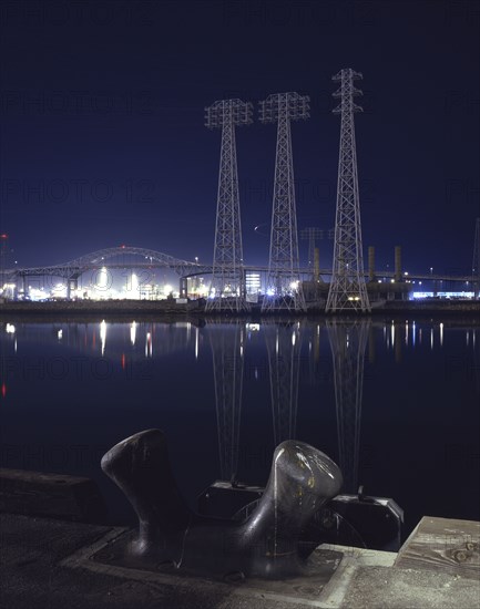 Reflection of metal towers in harbor at night