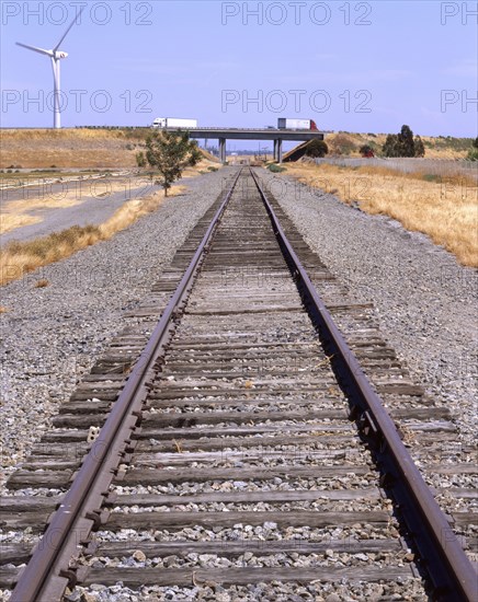 Wind turbine near train track and freeway overpass