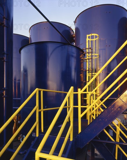 Yellow banisters on staircase near blue storage tanks