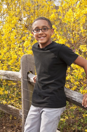 Mixed race boy leaning on fence