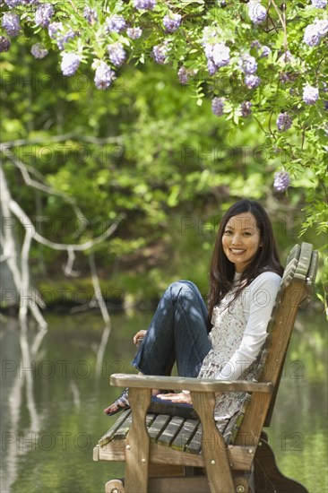 Asian woman sitting on bench in park