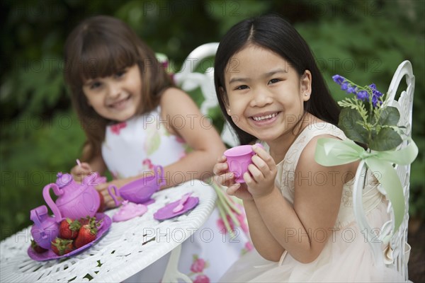 Mixed race girls having tea party in backyard