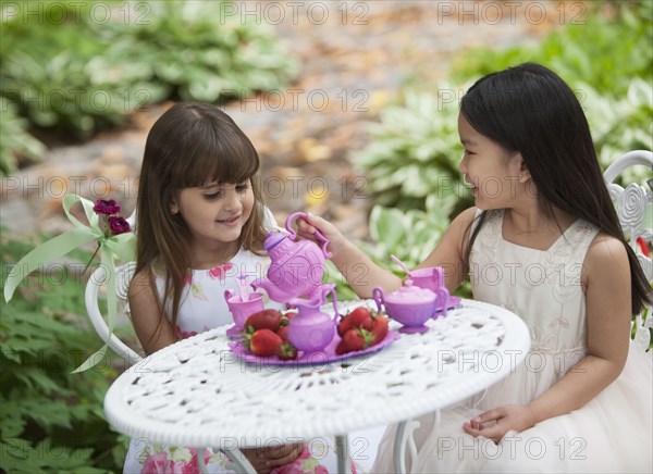 Mixed race girls having tea party in backyard