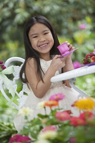 Mixed race girl having tea party in backyard