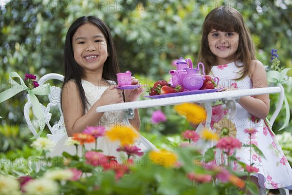 Mixed race girls having tea party in backyard