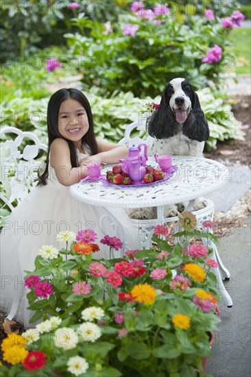 Mixed race girl and dog having tea party in backyard