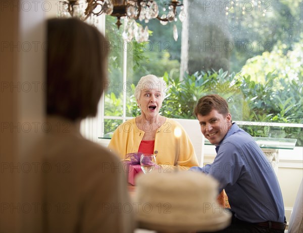 Caucasian woman surprising mother with birthday cake