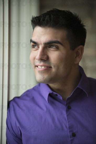 Hispanic businessman standing by window