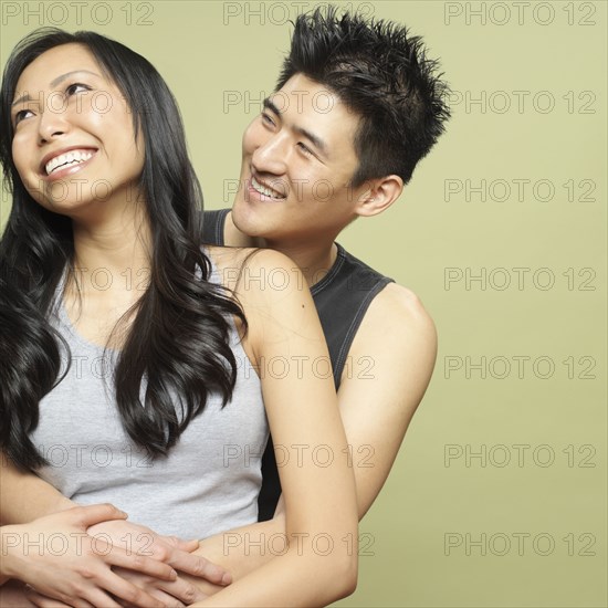 Studio shot of young Asian couple hugging