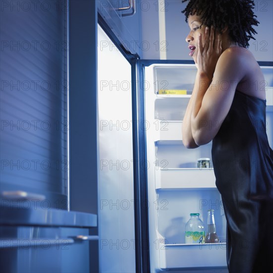 African woman looking in refrigerator with excitement