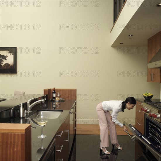 Asian woman looking in oven