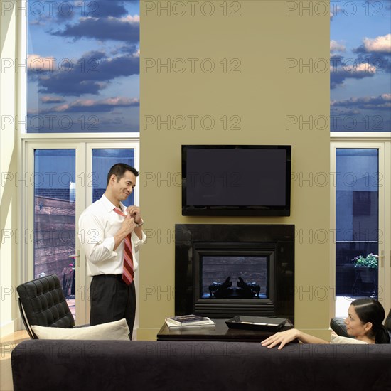 Asian man taking off tie and looking at wife