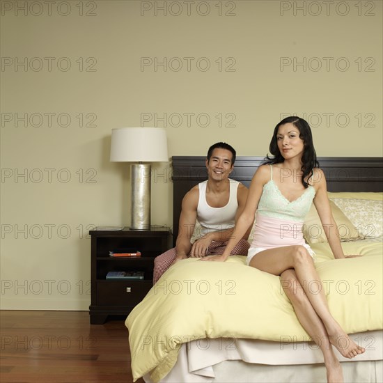 Asian couple sitting on bed