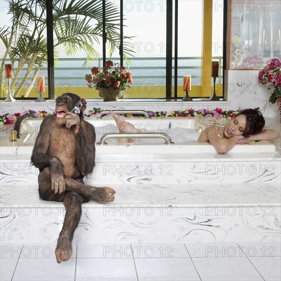 Monkey talking on cell phone while woman takes a bath