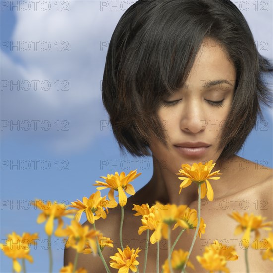 Mixed race woman smelling flowers