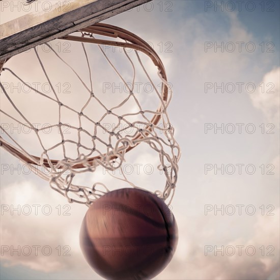 Basketball falling through hoop on court