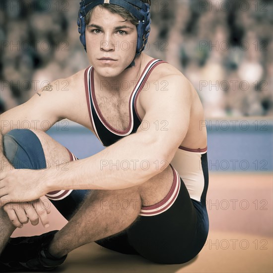 Caucasian wrestler sitting in ring